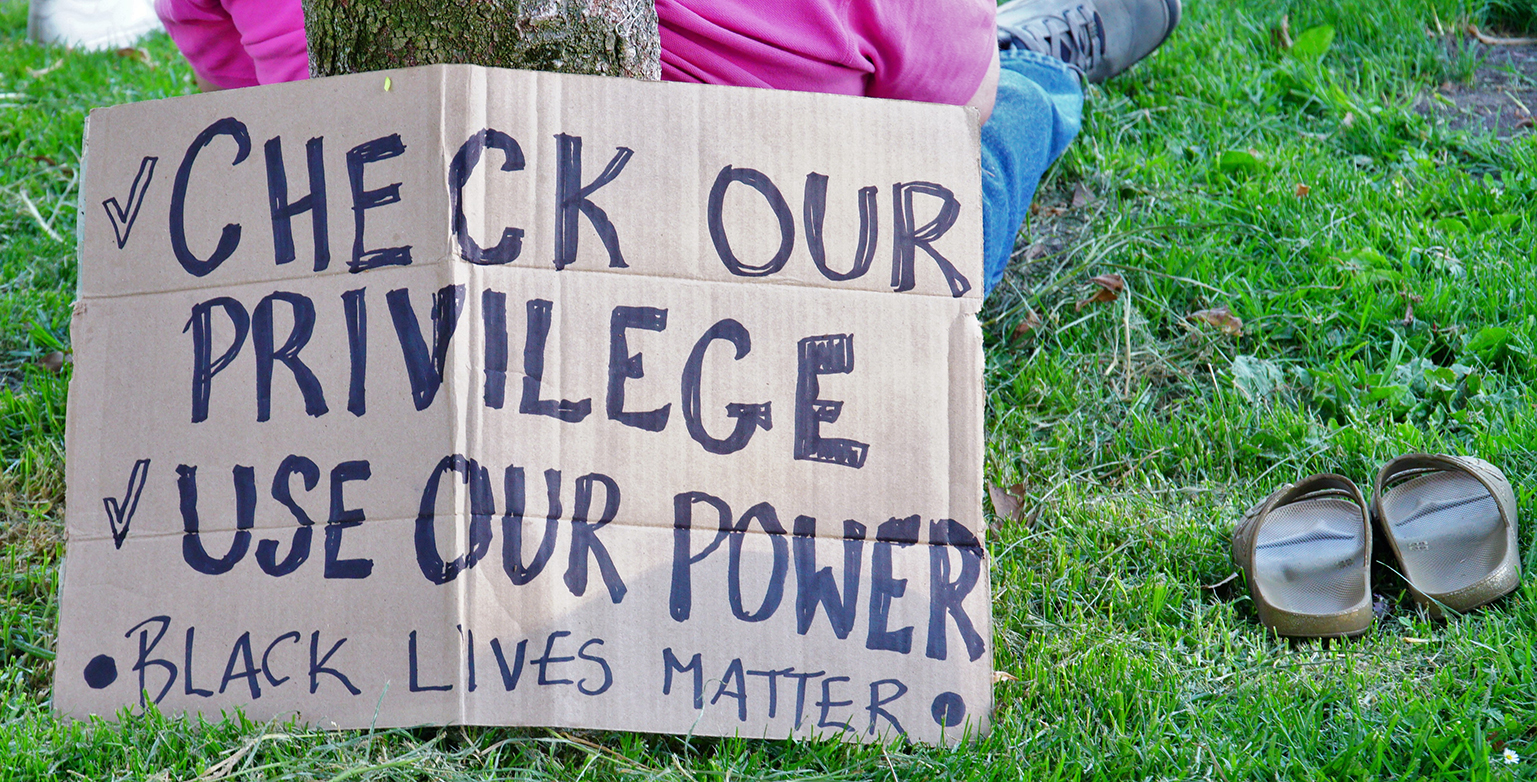 At a peaceful rally for social change an equality for everyone this handwritten cardboard sign was on display. Reads "Check our privilege. Use our power. Black Lives Matter.
